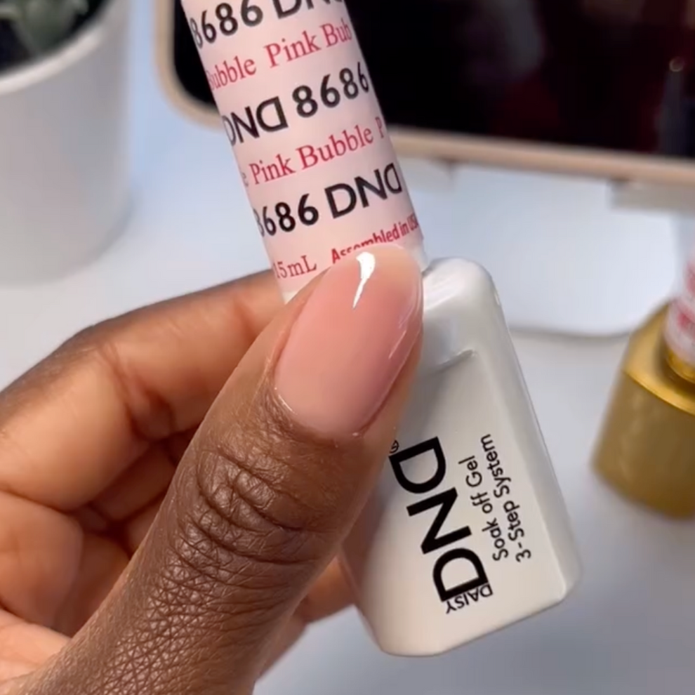 Manicured hand holding DND Pink Bubble #8686 gel polish bottle in porcelain pink sheer shade