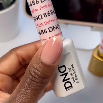 Manicured hand holding DND Pink Bubble #8686 gel polish bottle in porcelain pink sheer shade