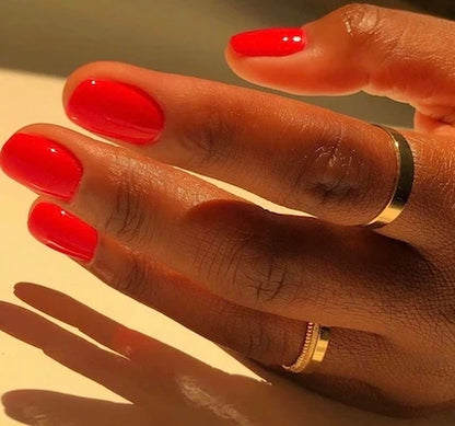 Hand wearing DND Red #563 gel polish, showing the classic neon red tone on the nails