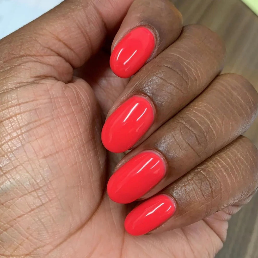 Manicured hands wearing DND Summer Hot Pink #414 jelly coral pink gel polish with glossy salon finish