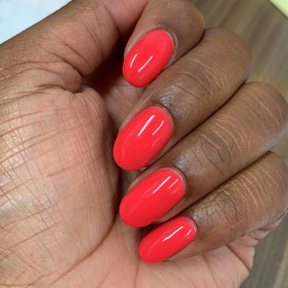 Manicured hands wearing DND Summer Hot Pink #414 jelly coral pink gel polish with glossy salon finish