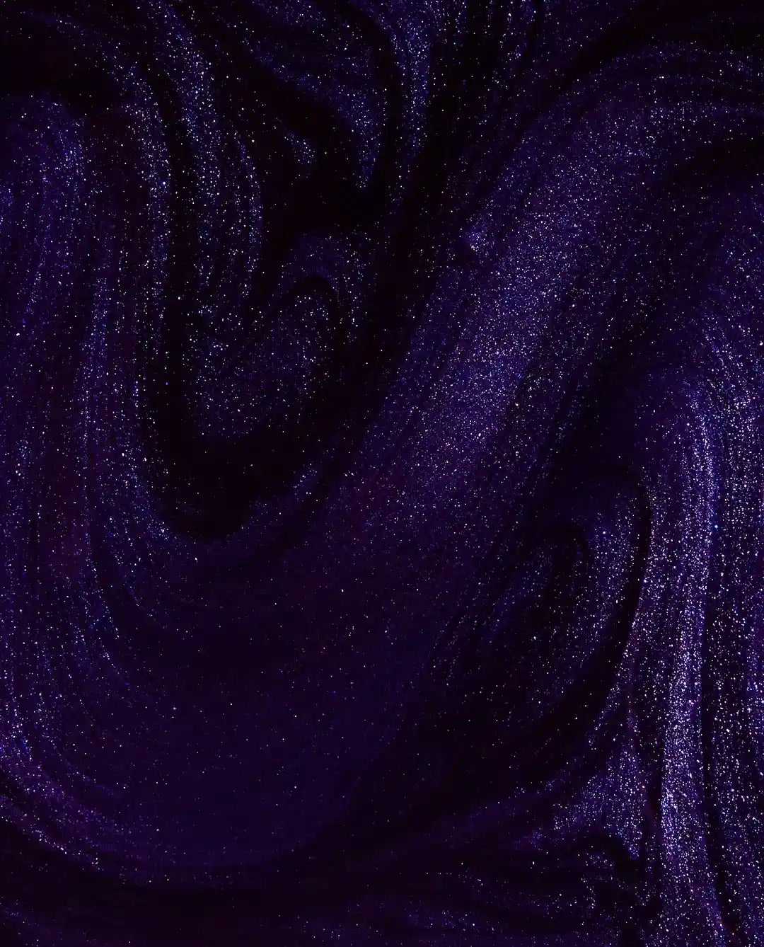 A close-up of a dark purple glittery liquid with swirling patterns and fine shimmer 