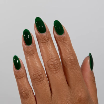 Manicured hand wearing DC Jelly 022 Emerald jelly gel polish to show the rich emerald green finish in natural light