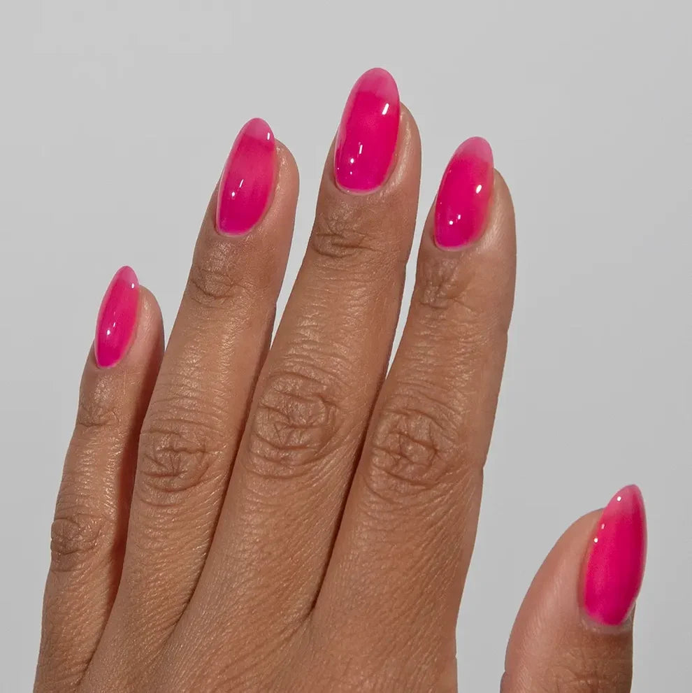 Manicured hand wearing DC Jelly 011 Hot Pink jelly gel polish to show the bold watermelon hot pink finish in natural light