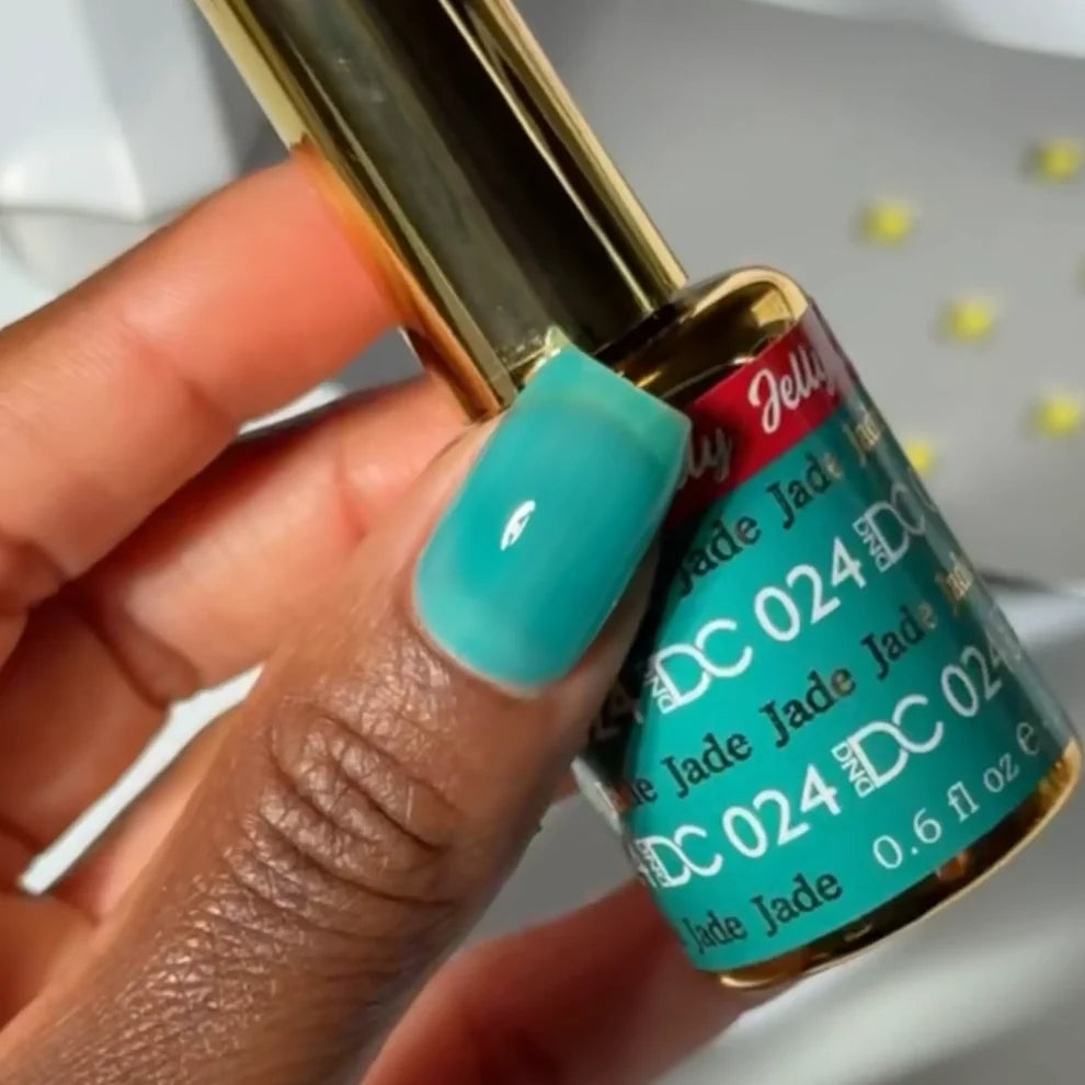 Manicured hand with dark skin tone wearing DC Jelly 024 Jade jelly gel polish in a turquoise green blue finish
