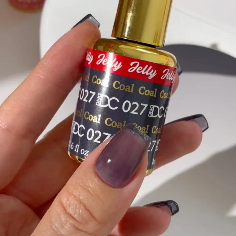 Manicured hand with light skin tone wearing DC Jelly 027 Coal jelly gel polish in a smoky dark grey finish