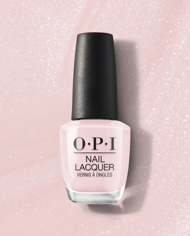 A bottle of OPI Nail Lacquer, Let Me Bayou a Drink in a pale pink shade, featuring a black cap and clear glass bottle, set against a sparkling light pink background.