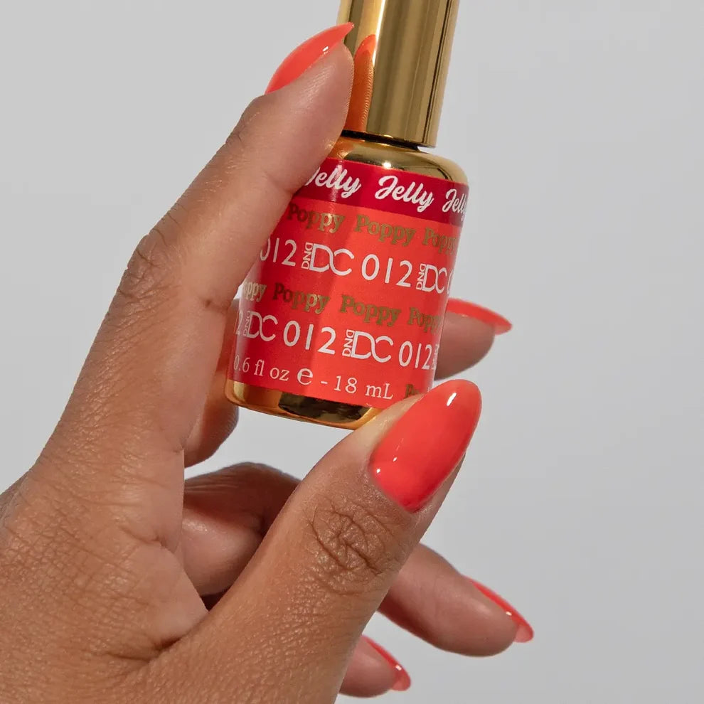Manicured hand holding the DC Jelly 012 Poppy jelly nail polish bottle, showcasing the vibrant coral red orange color on the nails
