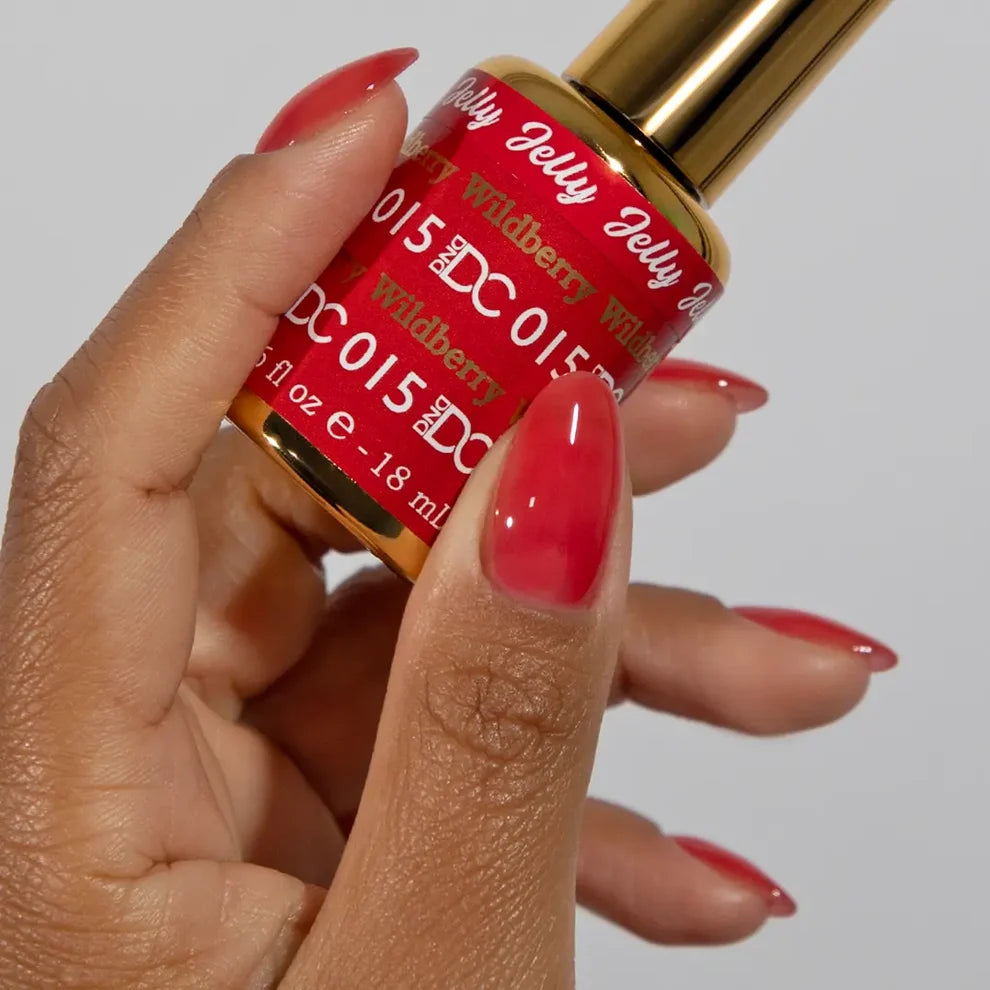 Manicured hand holding the DC Jelly 015 Wildberry jelly nail polish bottle, showcasing the strawberry red color on the nails