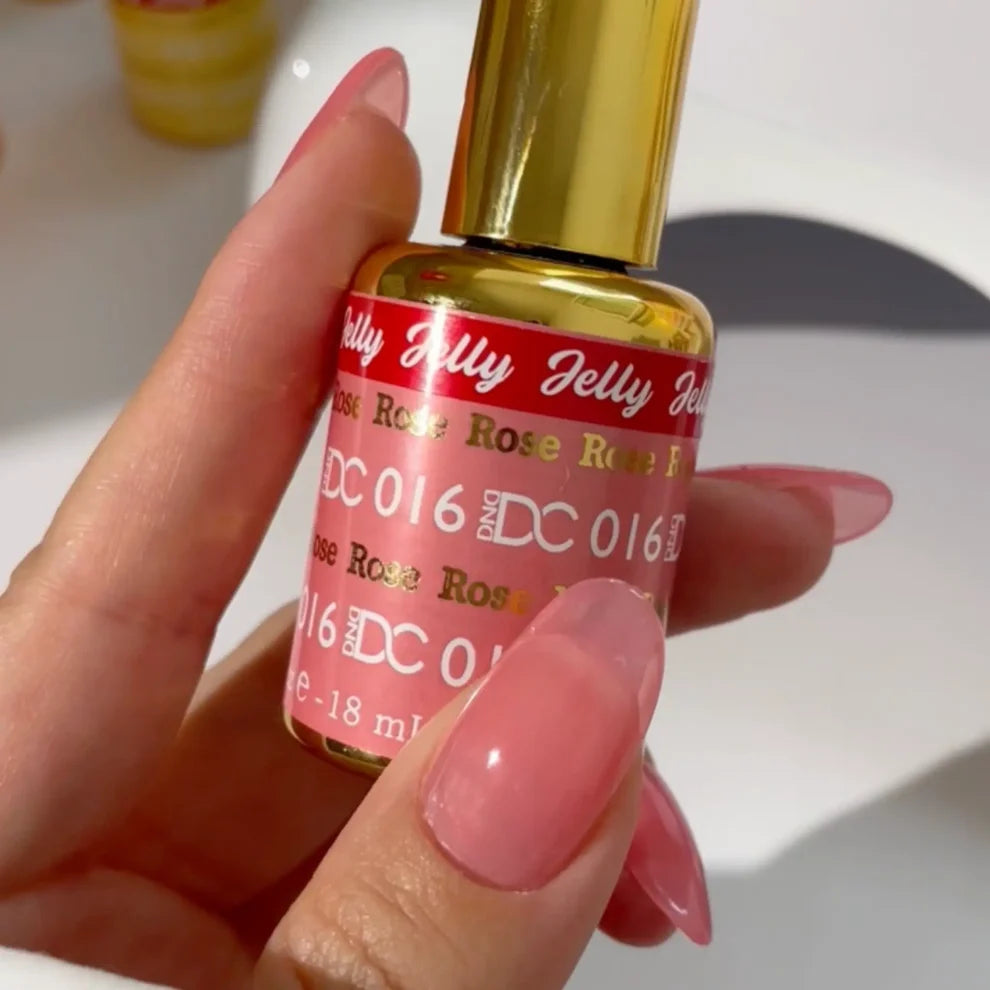 Manicured hand holding the DC Jelly 016 Rose jelly nail polish bottle, showcasing the pale pink color on the nails