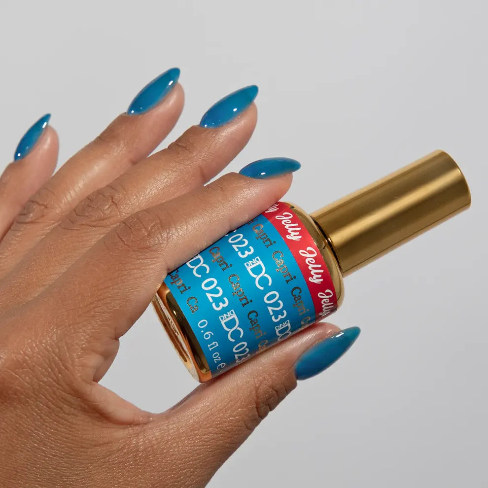 Manicured hand holding the DC Jelly 023 Capri jelly nail polish bottle, showcasing the bright azure blue color on the nails
