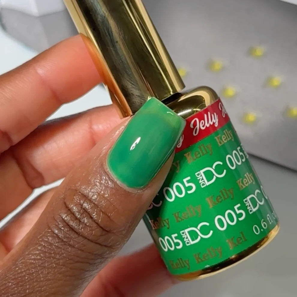 Manicured hand holding the DC Jelly 05 Kelly jelly gel polish bottle in green with blue undertones