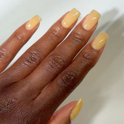 Manicured hand with dark skin tone wearing DC Jelly 08 Merengue Pie jelly gel polish in a soft pale yellow finish