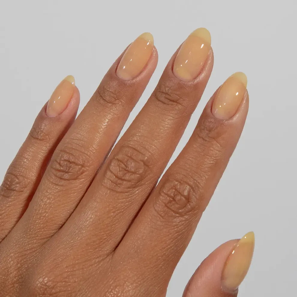 Manicured hand with light skin tone wearing DC Jelly 08 Merengue Pie jelly gel polish in a soft pale yellow finish