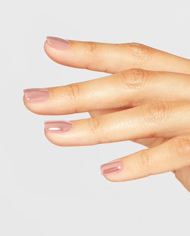 Manicured hand holding OPI F16 nude pink gel polish bottle showing the neutral finish