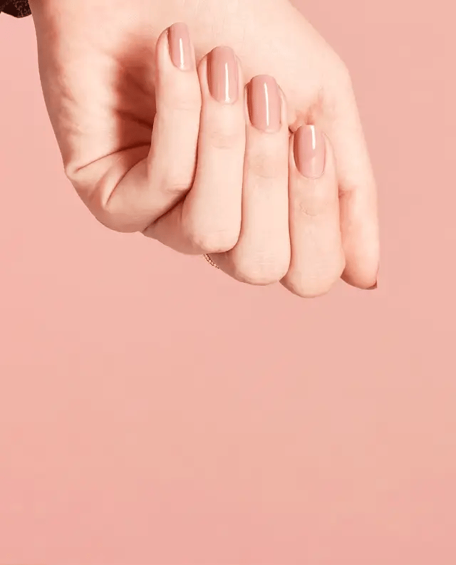 Manicured hand holding OPI F16 nude pink gel polish bottle showing the neutral finish