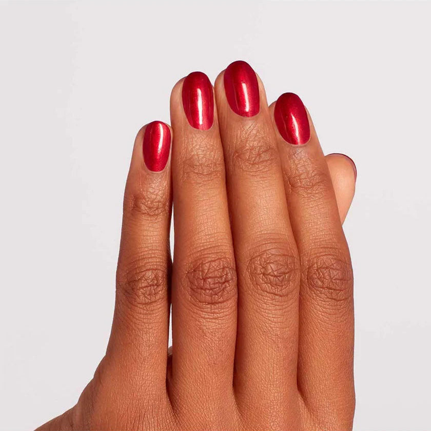 Classic manicure on hands displaying OPI A Little Guilt Under The Kilt red glossy finish with smooth coverage.