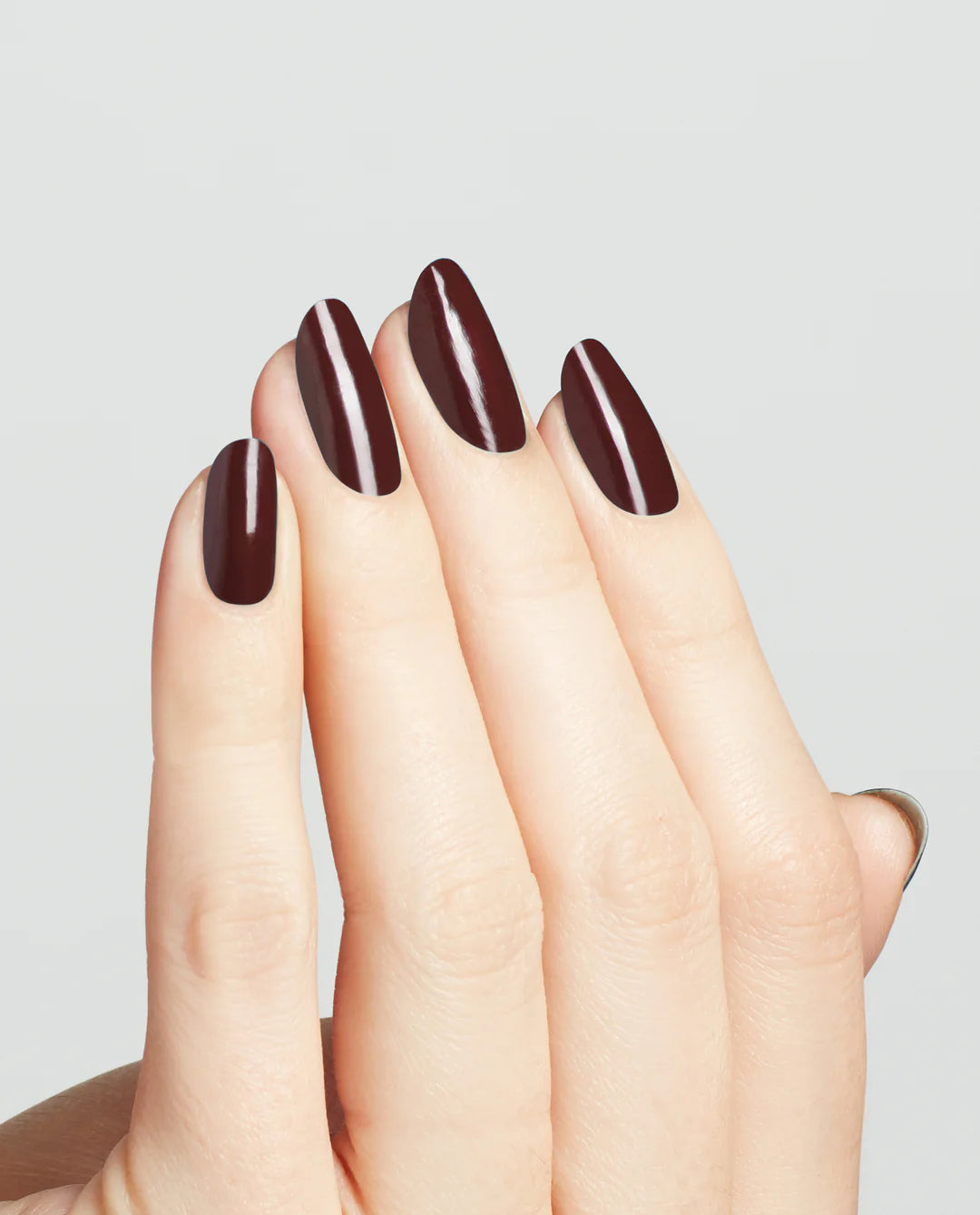 Professional manicure on natural nails showing OPI Complimentary Wine MI12 rich burgundy high-gloss finish and smooth application.