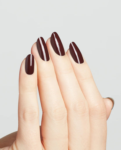 Professional manicure on natural nails showing OPI Complimentary Wine MI12 rich burgundy high-gloss finish and smooth application.