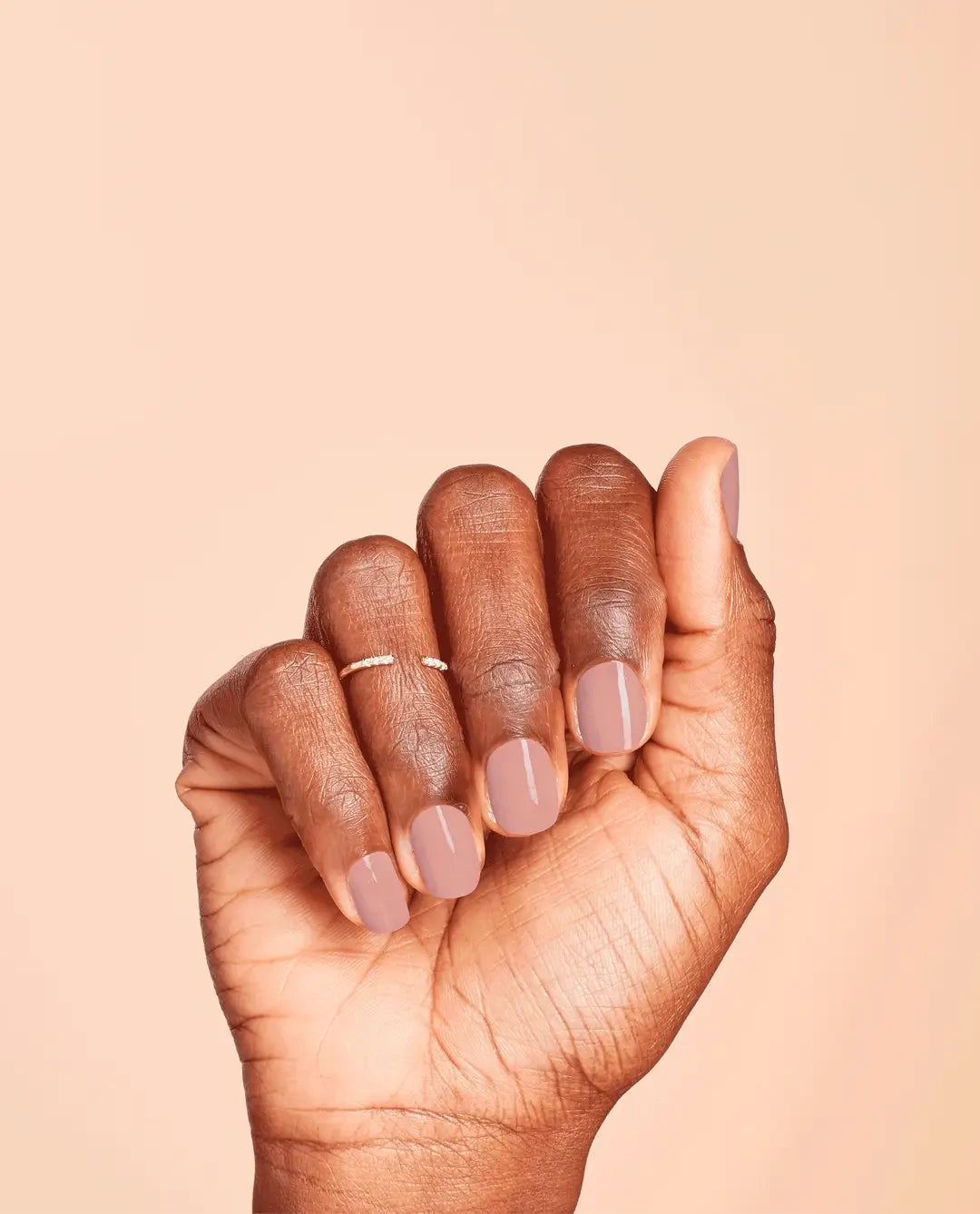 Hand with OPI Put It In Neutral Gel neutral pink beige gel polish for nail technicians on a beige background