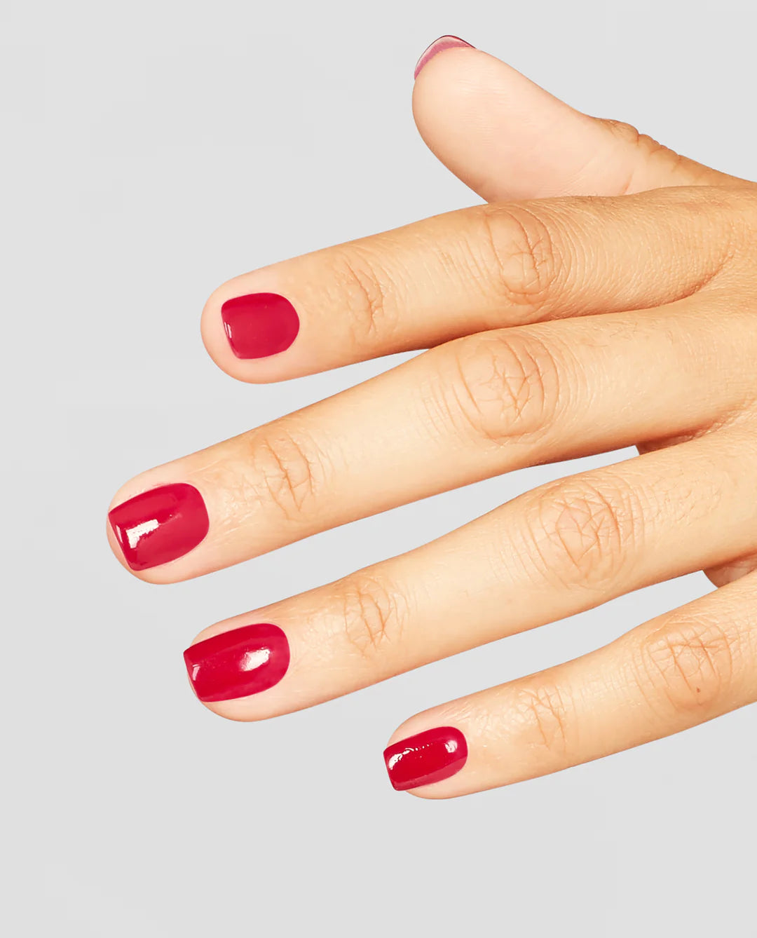 Hand with OPI red L72 red nail polish on a gray background