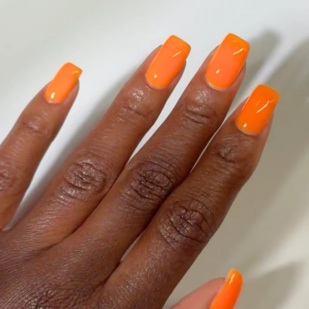 Manicured hand wearing DC Jelly 06 Orange jelly gel polish on dark skin to show the creamy jelly finish in natural light