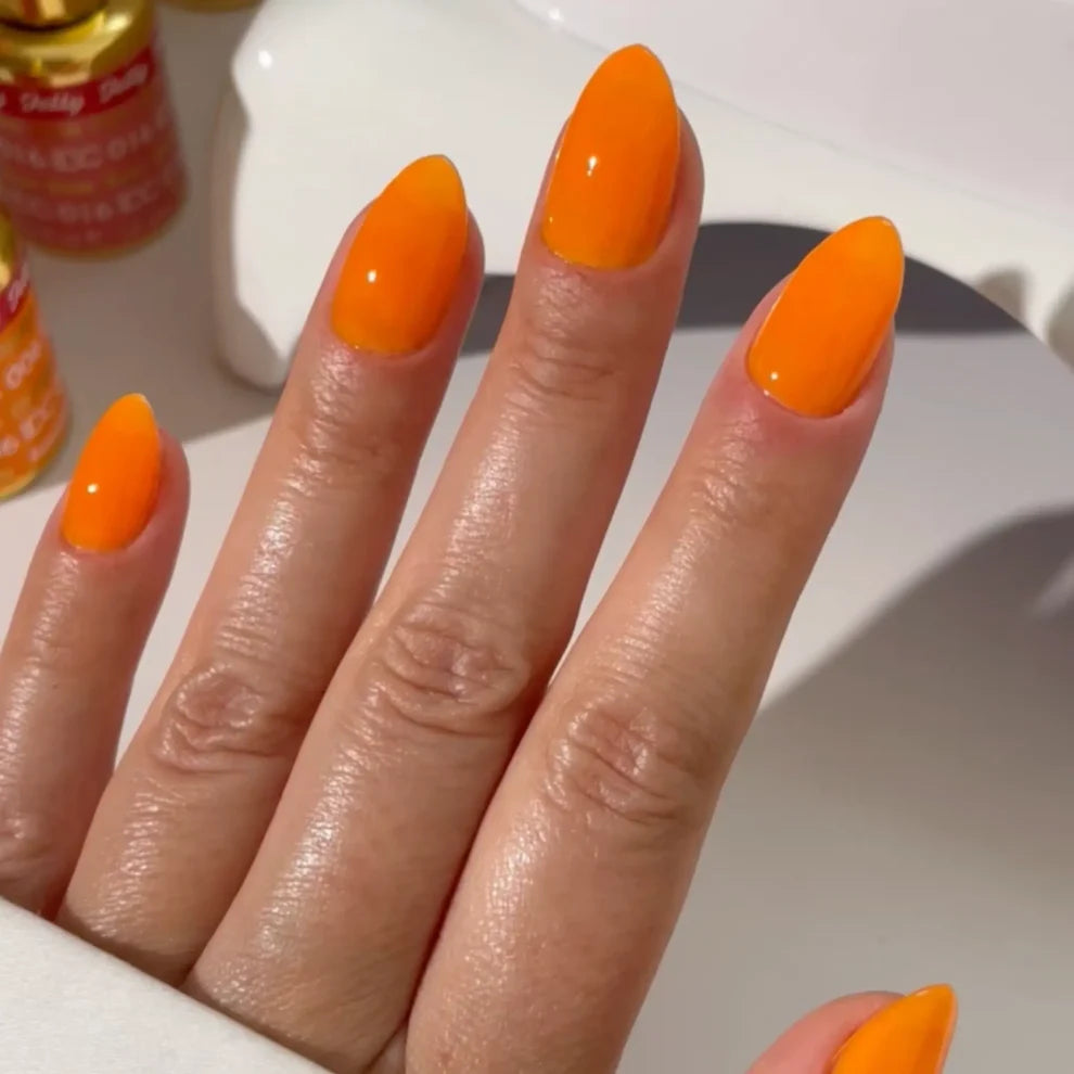 Manicured hand wearing DC Jelly 06 Orange jelly gel polish to show the creamy jelly finish in natural light