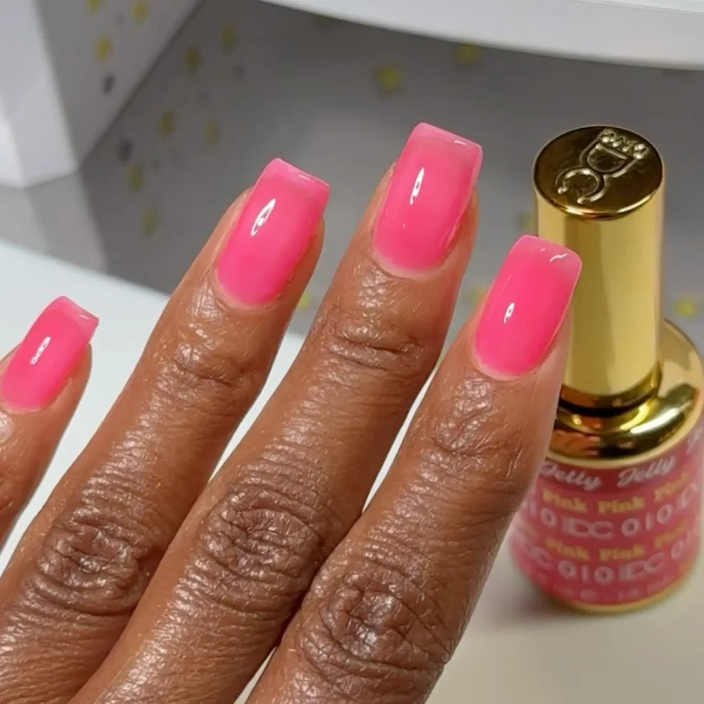 Manicured hand with dark skin tone wearing DC Jelly 010 Pink jelly gel polish in a bright watermelon pink finish