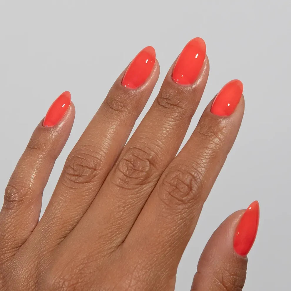 Manicured hand wearing DC Jelly 012 Poppy jelly gel polish to show the vibrant coral hot jelly finish in natural light