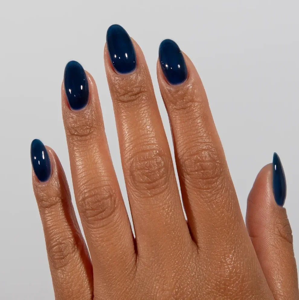 Manicured hand wearing DC Jelly 021 Sapphire jelly gel polish to show the deep sea teal blue finish in natural light