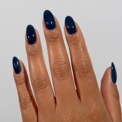 Manicured hand wearing DC Jelly 021 Sapphire jelly gel polish to show the deep sea teal blue finish in natural light