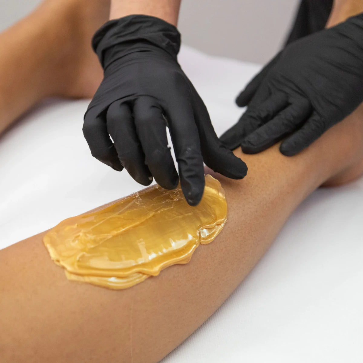 Technician applying Sharonelle hard wax to skin for professionals Canada