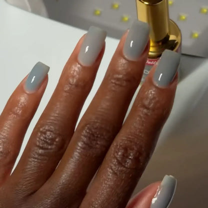 Manicured hand with dark skin tone wearing DC Jelly 025 Storm jelly gel polish in a warm grey finish