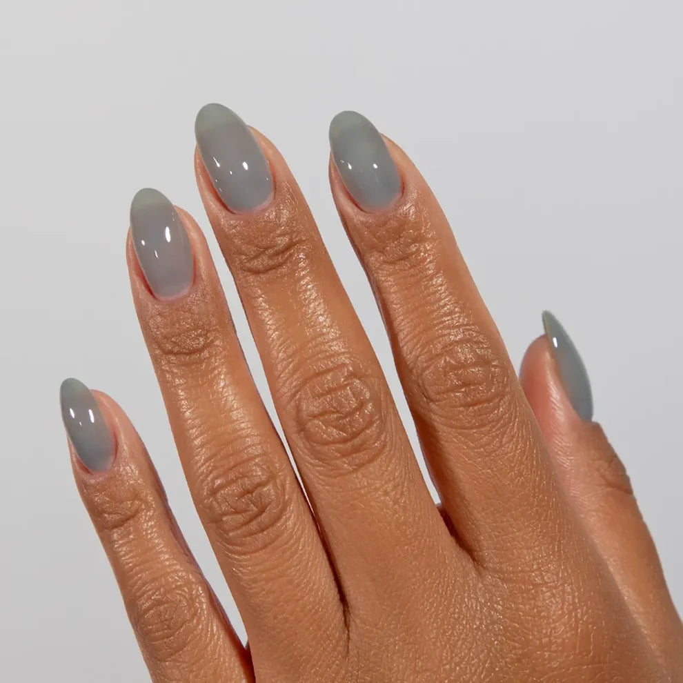 Manicured hand wearing DC Jelly 025 Storm jelly gel polish to show the cloudy warm grey finish in natural light