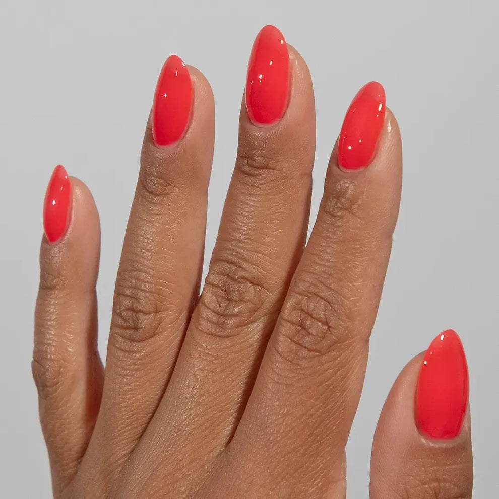 Manicured hand wearing DC Jelly 013 Tiger Blood jelly gel polish to show the warm coral creamy jelly finish in natural light