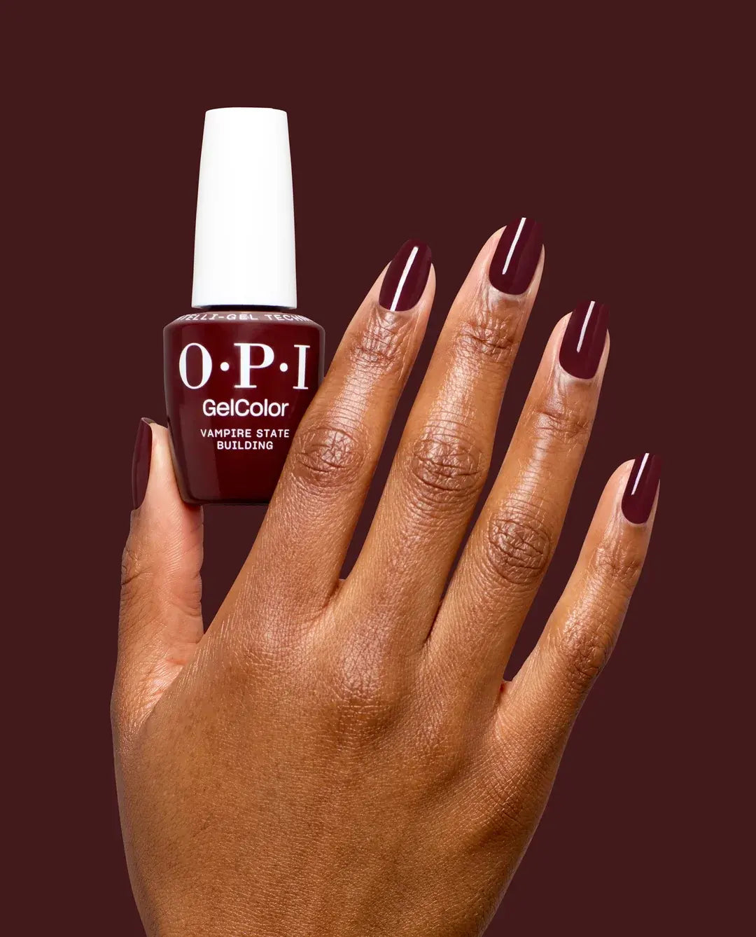 OPI nail polish bottle with a manicure hand wearing dark red nails against a dark background