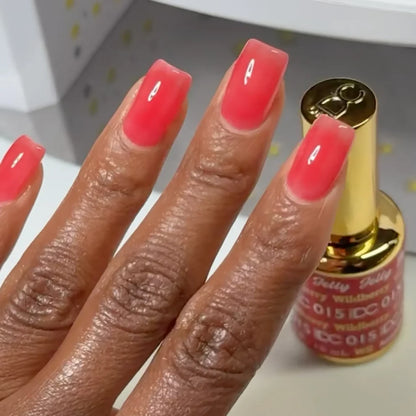 Manicured hand with dark skin tone wearing DC Jelly 015 Wildberry jelly gel polish in a strawberry red finish