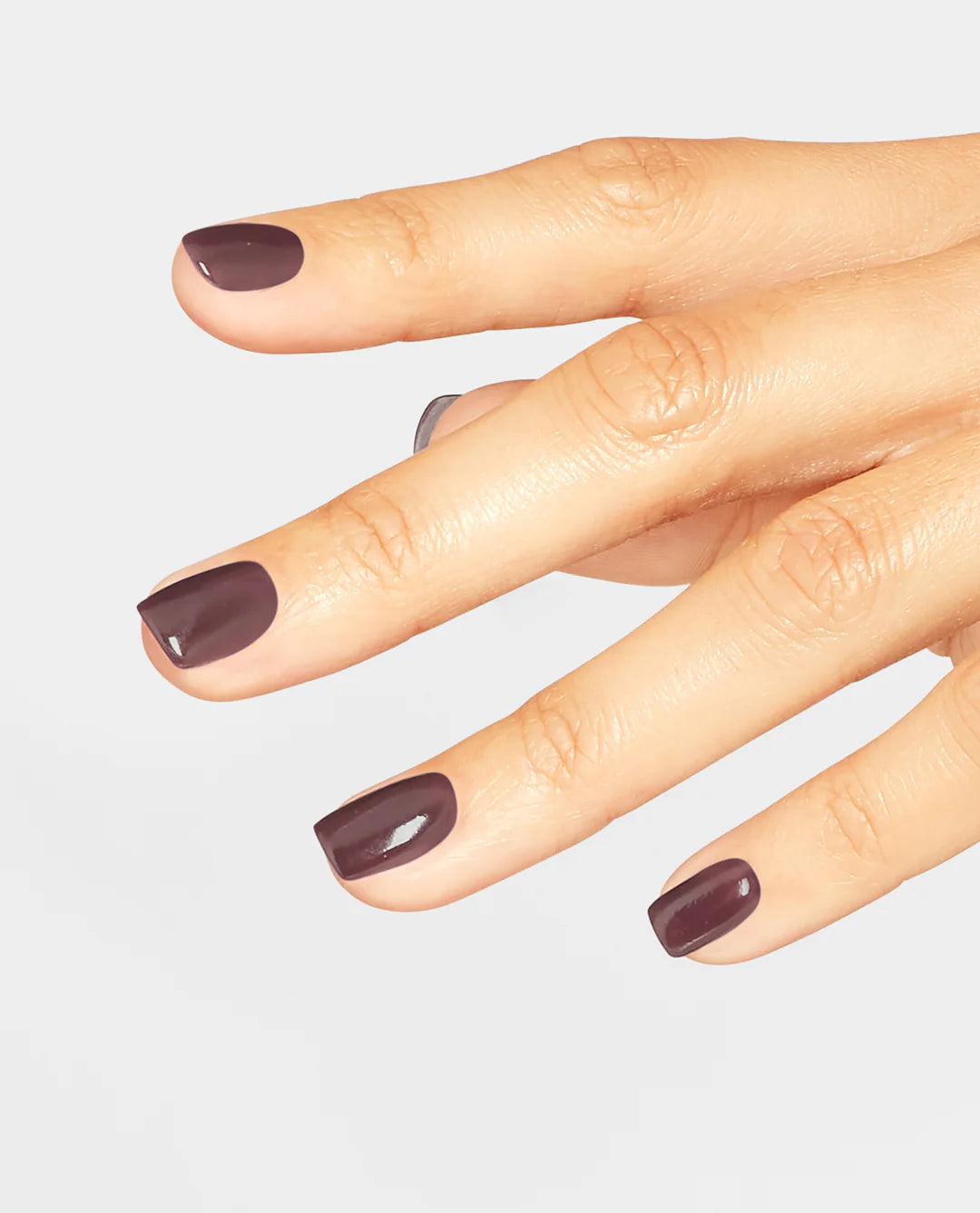 Hand with dark brown OPI GelColor You Don’t Know Jacques F15 professional gel polish nail polish on a light gray background