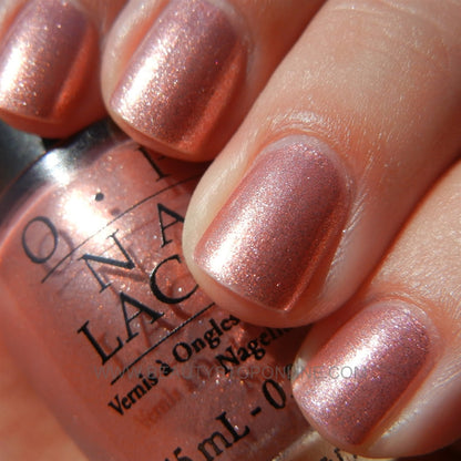 Tropical pink coral manicure with OPI Cozu-Melted In The Sun displayed in sunny vacation setting.